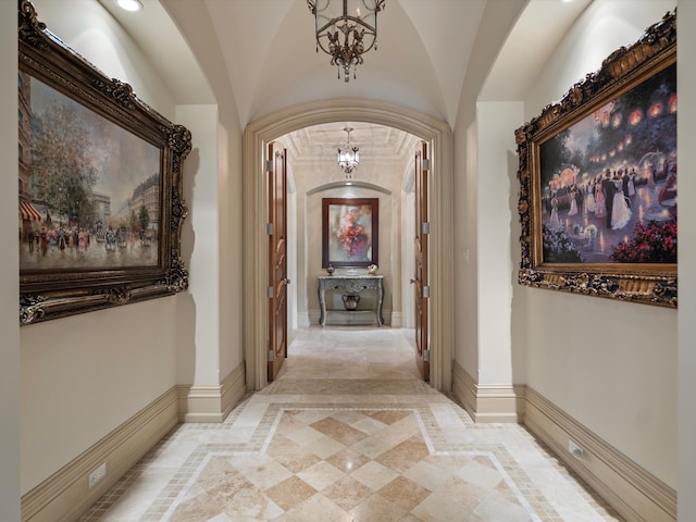 corridor featuring a notable chandelier, arched walkways, and baseboards