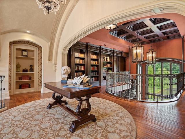 interior space featuring hardwood / wood-style flooring, a notable chandelier, coffered ceiling, built in features, and beamed ceiling