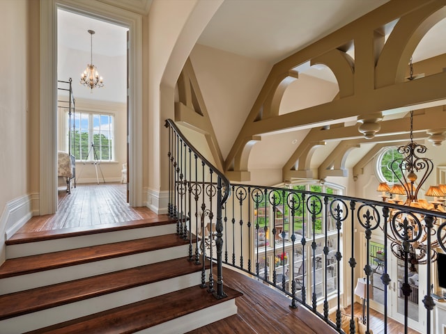 stairs featuring a notable chandelier, baseboards, and wood finished floors