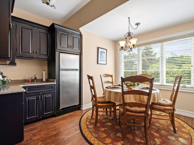 dining space with baseboards, dark wood finished floors, and an inviting chandelier