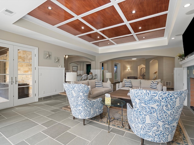 living area with arched walkways, visible vents, coffered ceiling, and wood ceiling