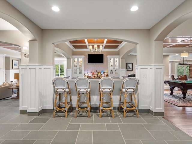 bar with coffered ceiling, pool table, tile patterned flooring, and a wainscoted wall