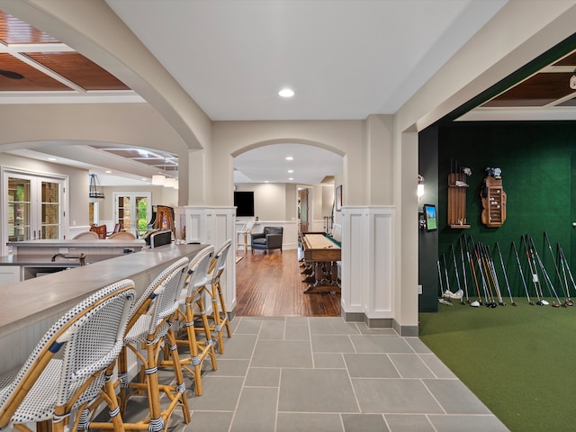 interior space with arched walkways, a wainscoted wall, a decorative wall, and recessed lighting