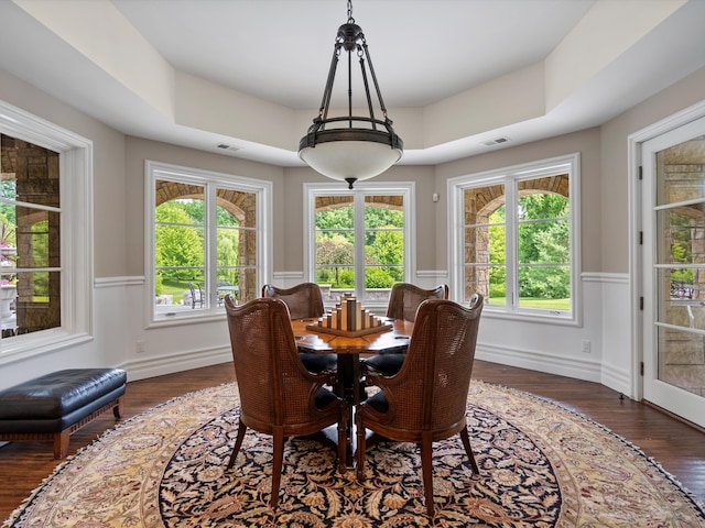 dining space with dark wood-type flooring, wainscoting, visible vents, and baseboards