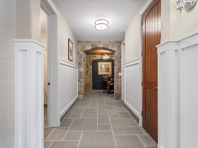 hallway featuring arched walkways and tile patterned flooring