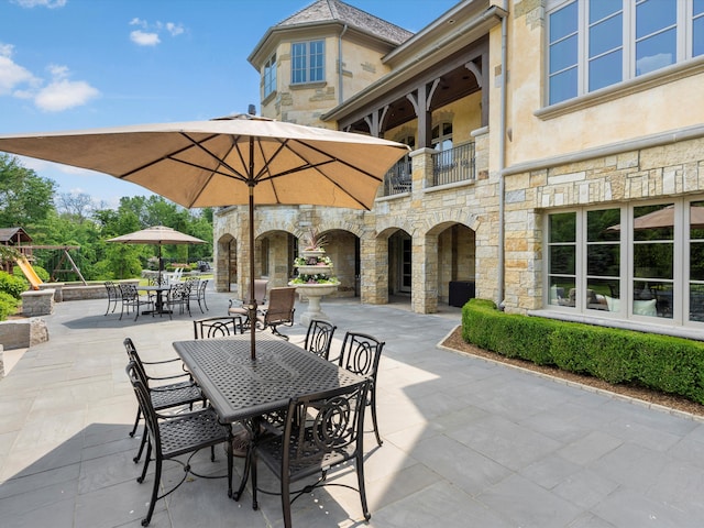 view of patio with a balcony and outdoor dining area