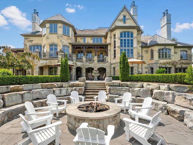 rear view of house with stone siding, an outdoor fire pit, and a patio area