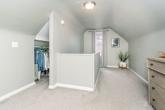 additional living space featuring light carpet, vaulted ceiling, and baseboards