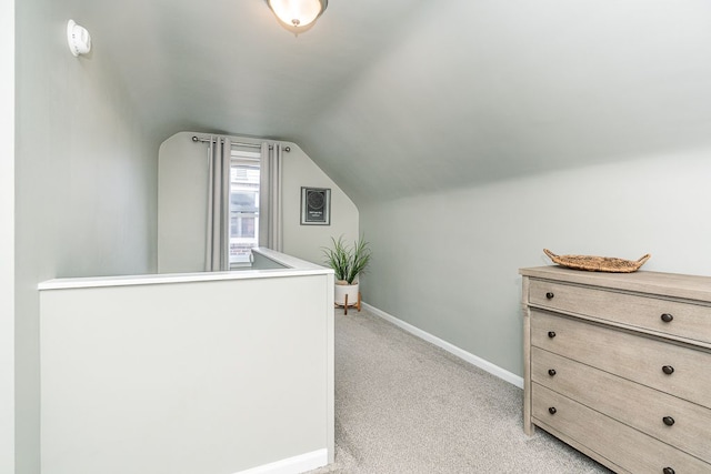 bonus room with baseboards, lofted ceiling, and light colored carpet