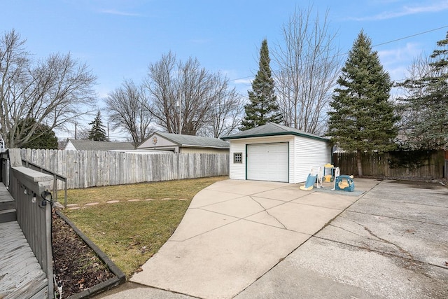 view of yard featuring a fenced backyard, an outdoor structure, driveway, and a detached garage