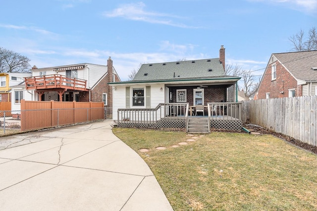 rear view of property with fence private yard, a shingled roof, a chimney, and a lawn