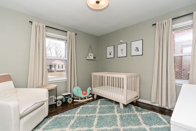 bedroom with a crib, baseboards, and wood finished floors