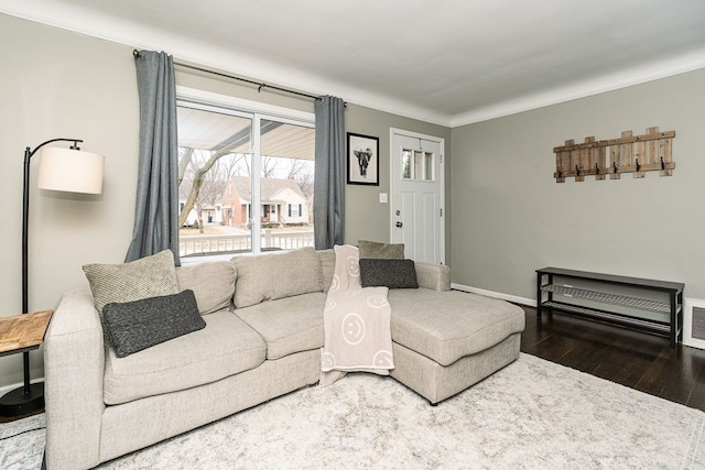 living area with hardwood / wood-style flooring, visible vents, baseboards, and crown molding