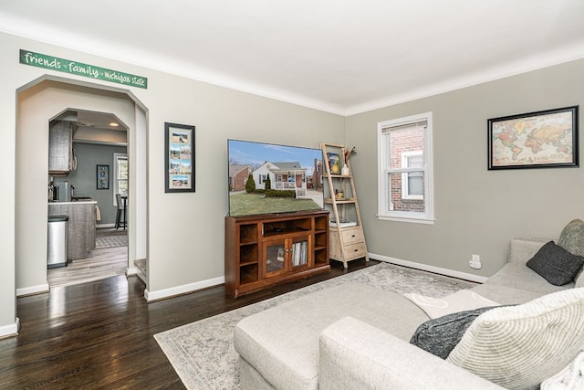 living room featuring baseboards, arched walkways, and wood finished floors