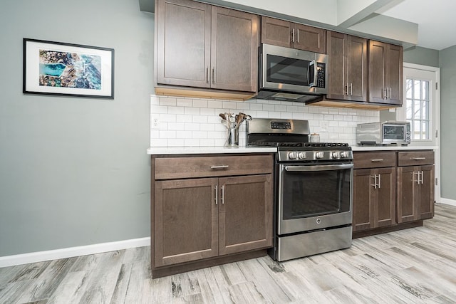 kitchen featuring stainless steel appliances, light countertops, light wood-style flooring, and decorative backsplash