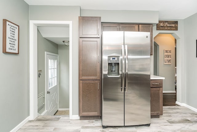 kitchen with arched walkways, stainless steel refrigerator with ice dispenser, and baseboards