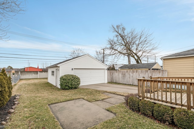 view of yard featuring a detached garage, fence, a deck, and an outbuilding