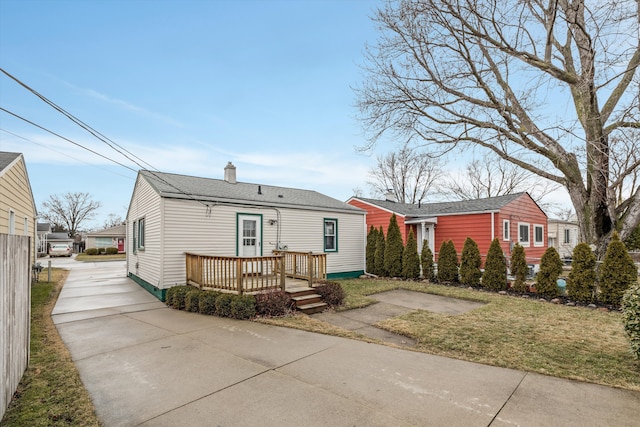 view of front of property with a chimney, fence, a deck, and roof with shingles