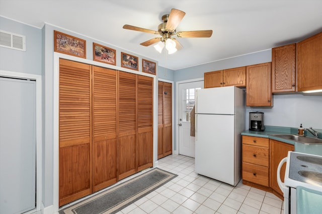 kitchen featuring white appliances, visible vents, brown cabinets, and a sink