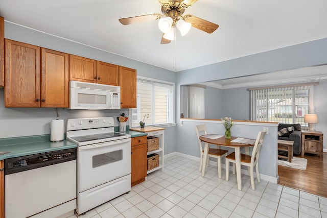 kitchen featuring white appliances, light tile patterned floors, baseboards, and brown cabinetry