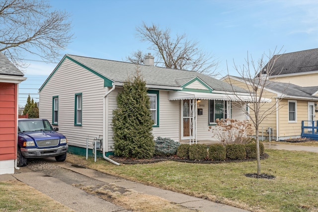 view of front of home with a chimney, a front lawn, and roof with shingles