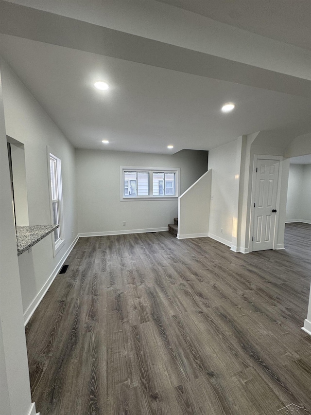 basement featuring baseboards, visible vents, stairway, dark wood-type flooring, and recessed lighting