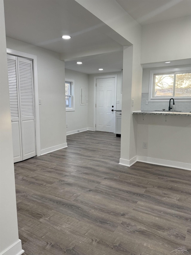 interior space featuring dark wood-style flooring, recessed lighting, a sink, and baseboards