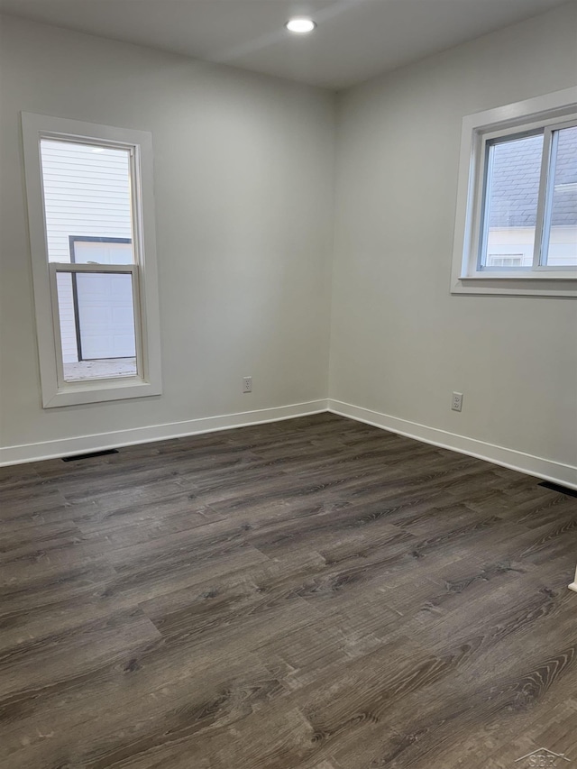 spare room featuring dark wood-style floors, visible vents, baseboards, and recessed lighting