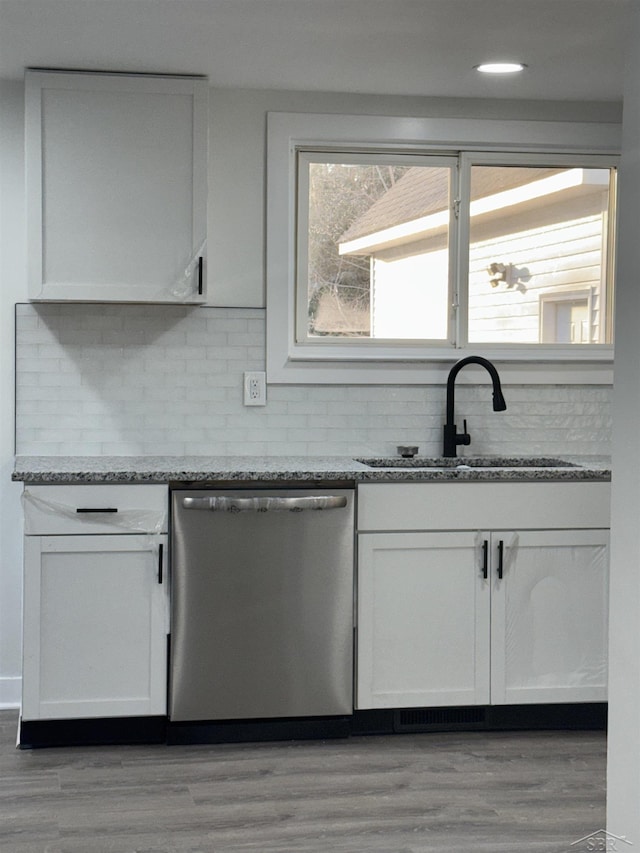 kitchen with decorative backsplash, a sink, stainless steel dishwasher, and light stone countertops