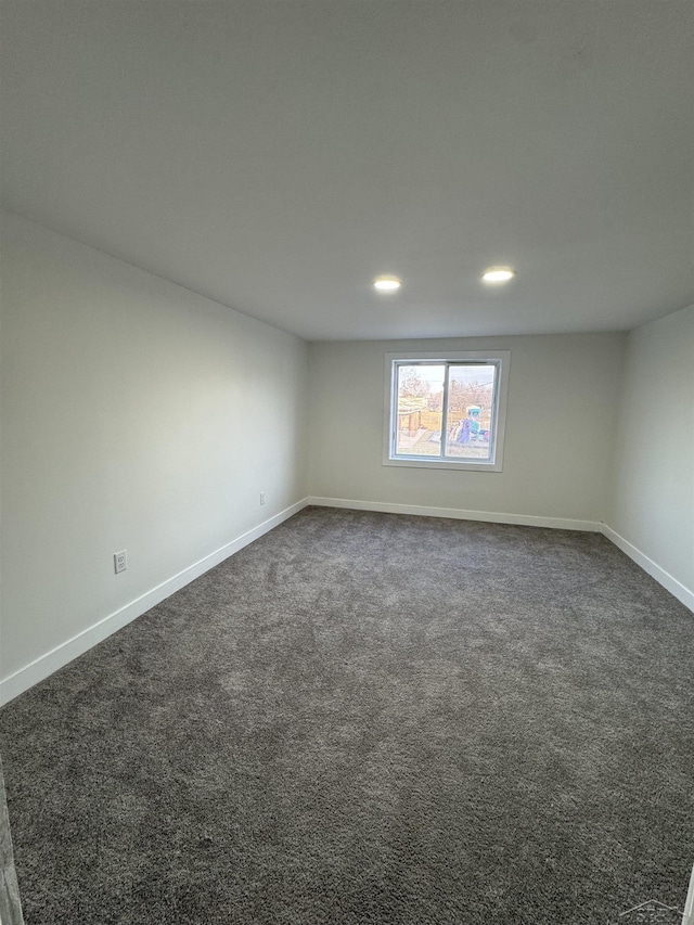 empty room featuring dark colored carpet, recessed lighting, and baseboards