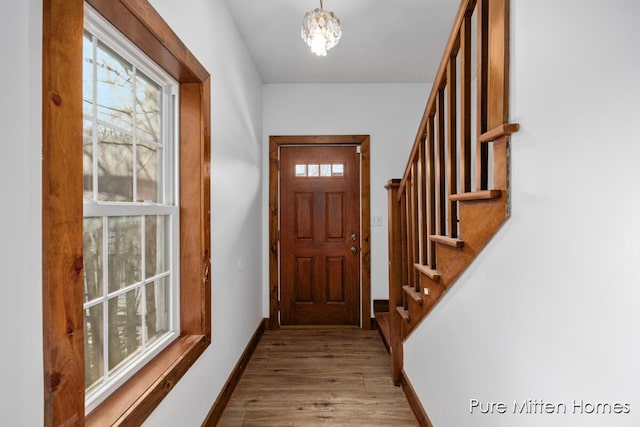 entryway featuring stairs, a wealth of natural light, baseboards, and wood finished floors