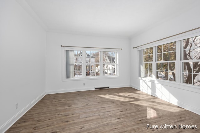 unfurnished room with visible vents, baseboards, and wood finished floors