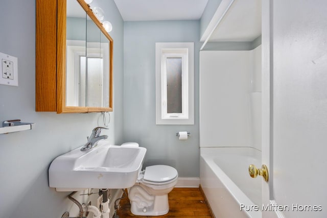 full bath featuring shower / tub combination, toilet, wood finished floors, a sink, and baseboards