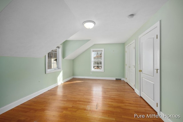 additional living space featuring vaulted ceiling, wood finished floors, visible vents, and baseboards