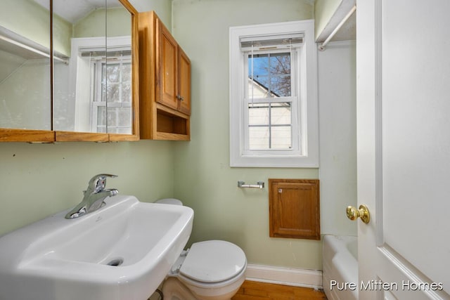 full bathroom featuring a tub to relax in, toilet, wood finished floors, a sink, and baseboards