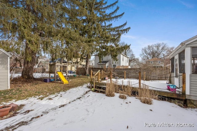 yard covered in snow featuring a playground and fence