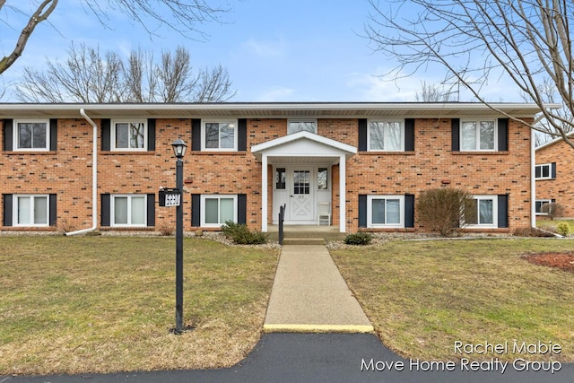 raised ranch featuring brick siding and a front yard