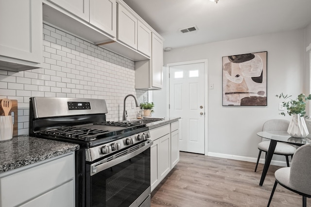 kitchen with stainless steel gas stove, light wood-style flooring, visible vents, and white cabinetry