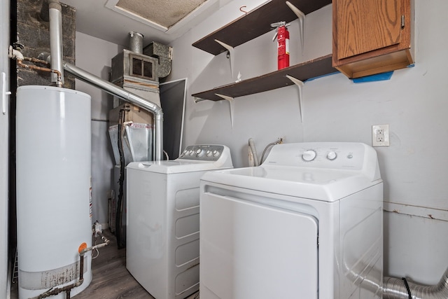 washroom featuring water heater, wood finished floors, washing machine and clothes dryer, and cabinet space