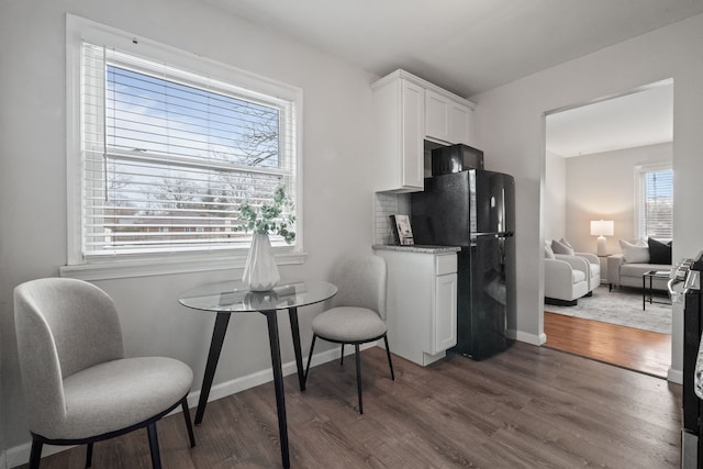 kitchen featuring dark wood-style floors, baseboards, white cabinetry, and freestanding refrigerator