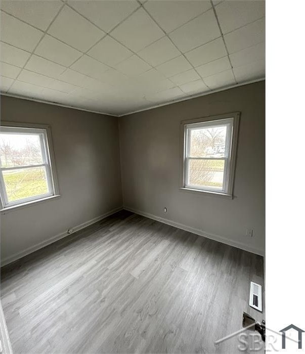 spare room with plenty of natural light, visible vents, and wood finished floors