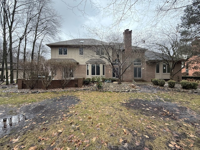 back of property with brick siding and a chimney