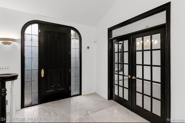 entryway featuring lofted ceiling, marble finish floor, arched walkways, and french doors