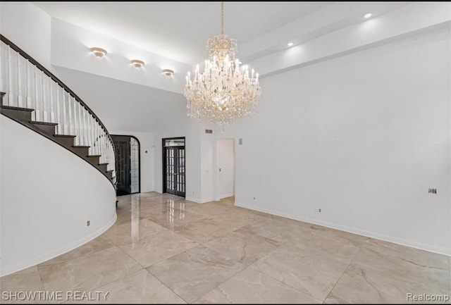 interior space featuring baseboards, marble finish floor, a high ceiling, stairs, and a notable chandelier