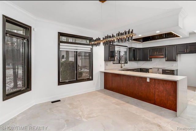 kitchen with visible vents, a peninsula, light countertops, crown molding, and a sink