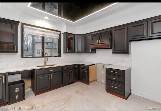 kitchen featuring backsplash, a sink, and glass insert cabinets