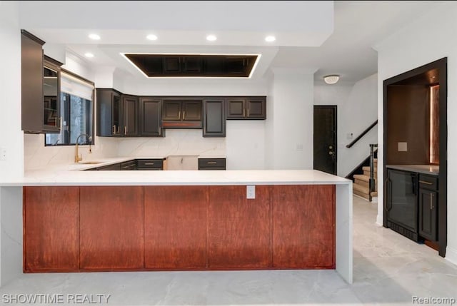 kitchen featuring tasteful backsplash, a peninsula, light countertops, a sink, and recessed lighting