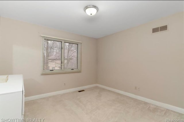 unfurnished room featuring light colored carpet, visible vents, and baseboards