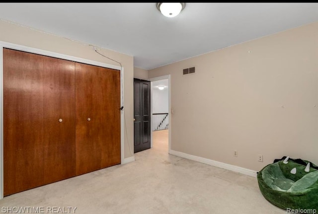 unfurnished bedroom featuring light carpet, a closet, visible vents, and baseboards