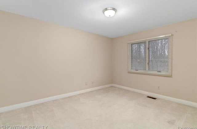 spare room featuring carpet floors, visible vents, and baseboards